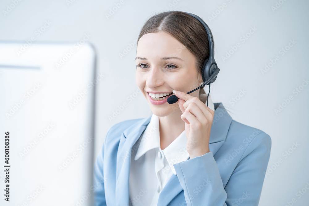 Friendly smiling female call-center agent with headset working on support hotline in office. Friendly smiling female call-center agent with headset working on support hotline in office.