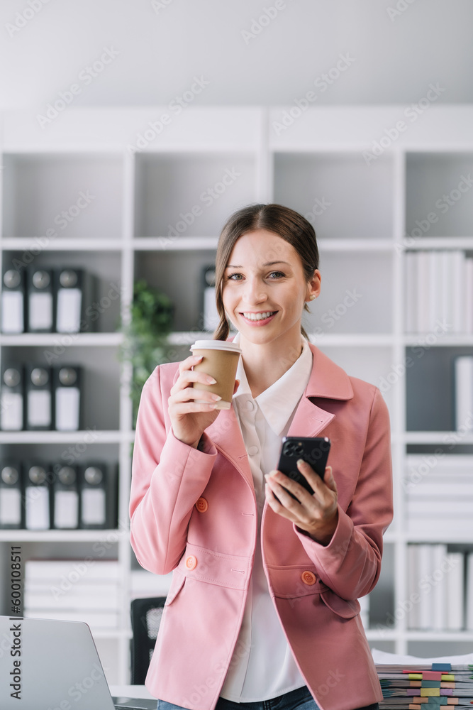 portrait of a business woman Self-confident young woman standing holding coffee mug and working smartphone. People. Straightforward portrait. Casual business. Self-confidence. leadership concept. portrait of a business woman Self-confident young woman standing holding coffee mug and working smartphone. People. Straightforward portrait. Casual business. Self-confidence. leadership concept.