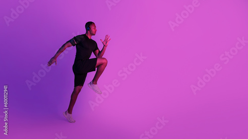 Sporty African American Guy Exercising Wearing Headphones Over Purple Background