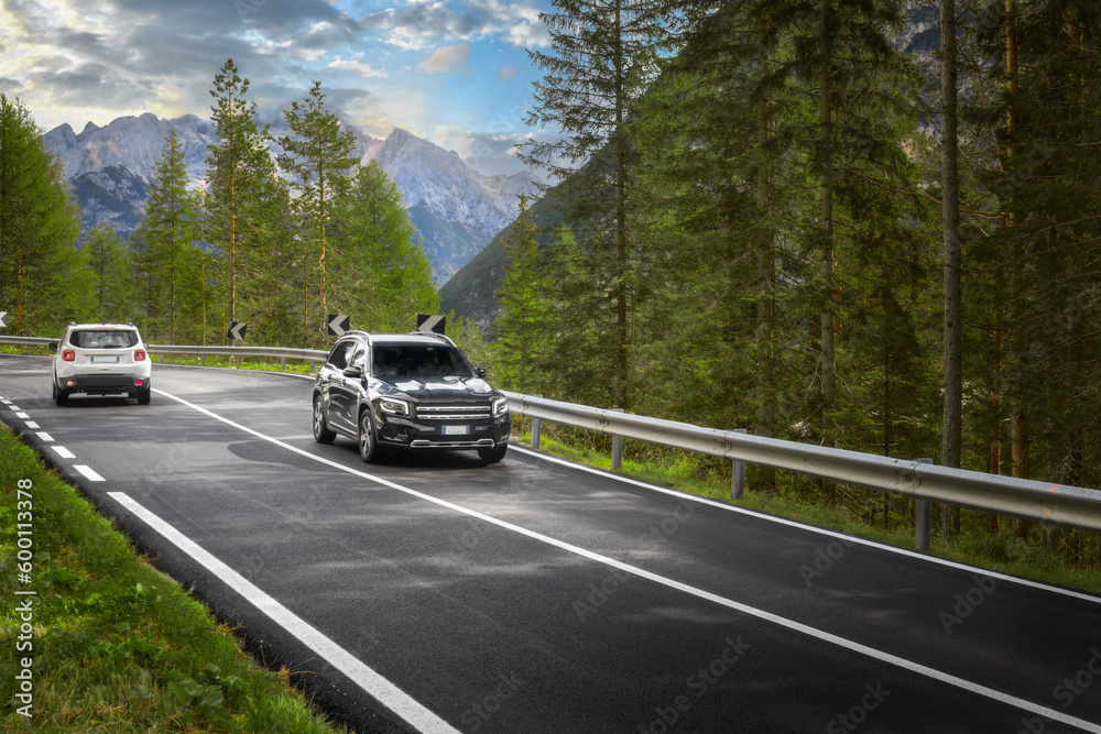 Modern car drive on asphalt road a sunny day in the morning at dawn in the mountains Dolomites Alps, Italy. Travel concept