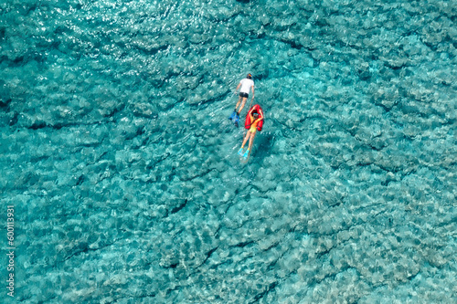 Summer family vacation holiday concept. Father and daughter swimming together in the clear blue sea, snorkeling