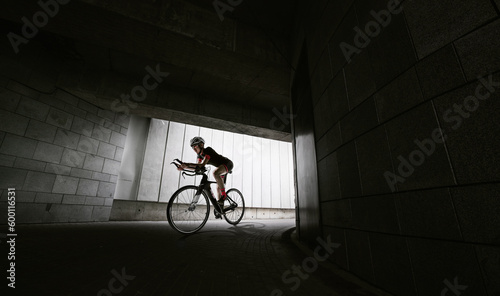 The cyclist rides on her road bike at dark tonel. Dramatic background. 