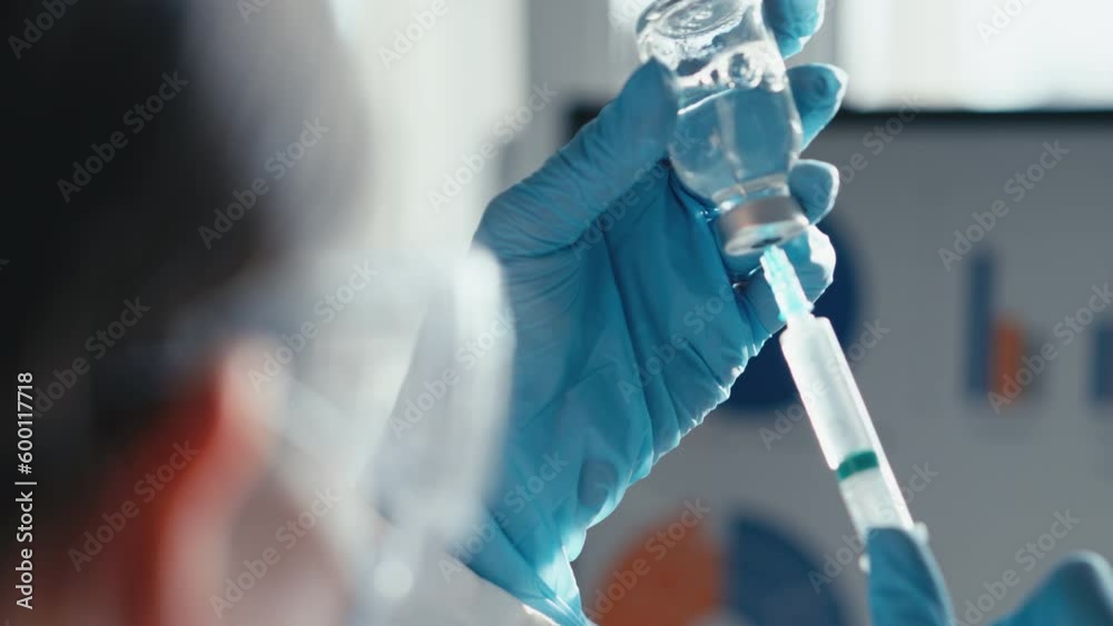 A doctor in a medical laboratory types a doctor into a syringe for injection in a close-up. Laboratory tests on the video show the process of testing for a new drug. Chemical research