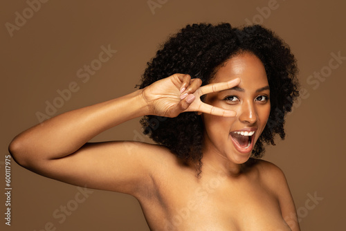 Playful half-naked african woman posing on brown background