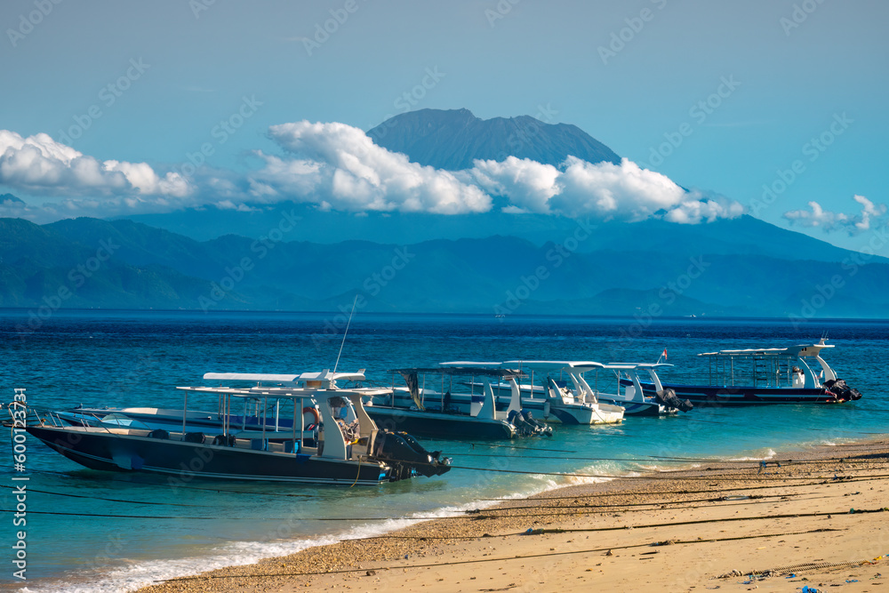 Obraz premium Passenger boats in Nusa Penida with the iconic Mount Agung (Gunung Agung) volcano on mainland Bali in the background, Indonesia