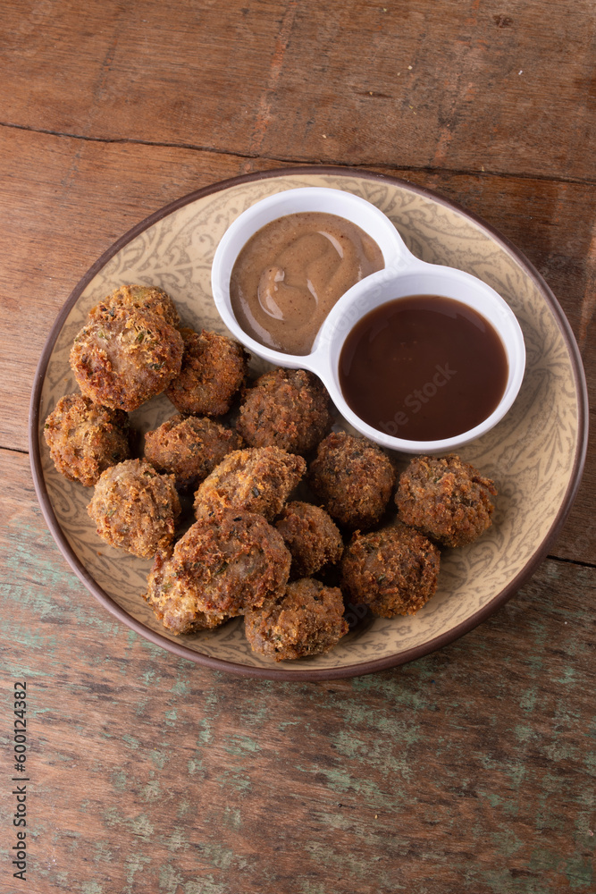 appetizer portion of pub tapas meatloaf dumpling or mini kafta kibis with black mustard and barbecue sauce on rustic wooden table top view appetizer portion of pub tapas meatloaf dumpling or mini kafta kibis with black mustard and barbecue sauce on rustic wooden table top view
