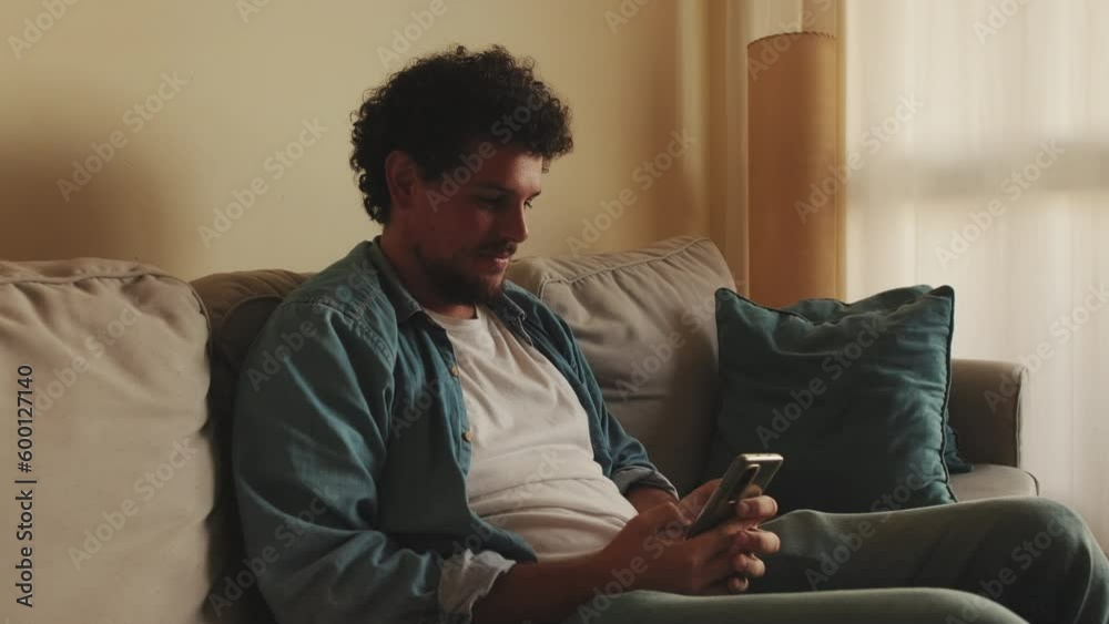 Young man using mobile phone while sitting in the living room