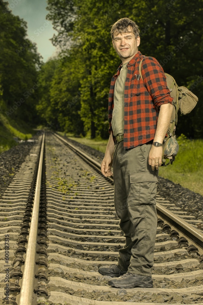 Fototapeta premium Adventurer with retro haversack wandering nature on railroad way