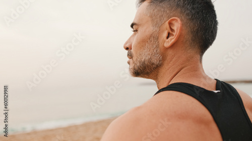 Close-up of middle-aged athletic man standing on the beach after workout and looking at the seascape © Andrii Nekrasov