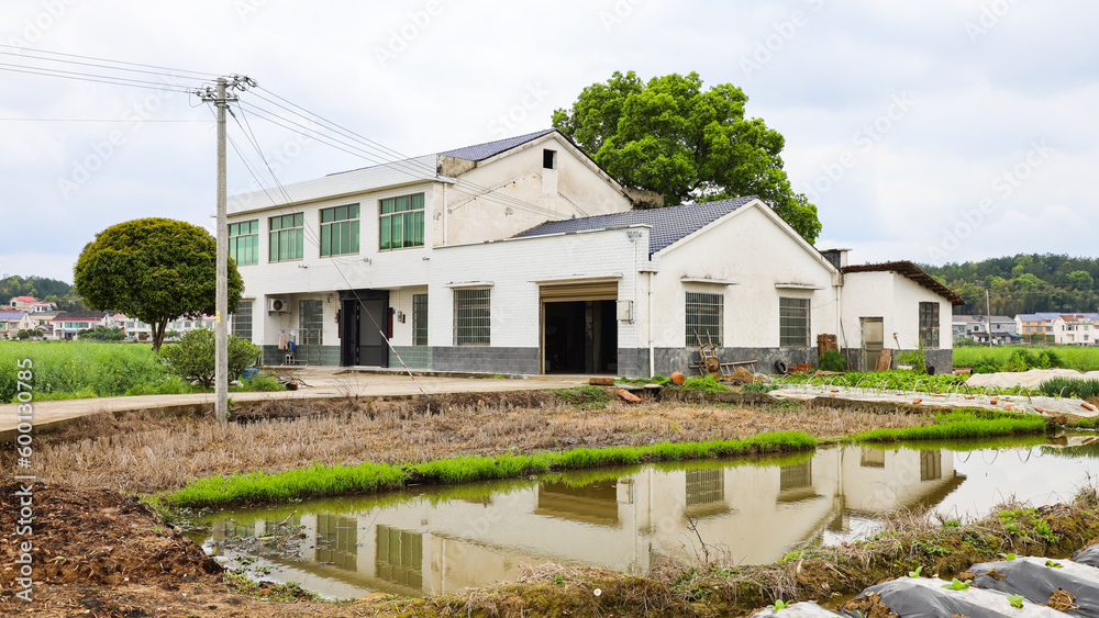 White Village house under moving clouds, with reflection in water pond, in Hunan Province, China White Village house under moving clouds, with reflection in water pond, in Hunan Province, China