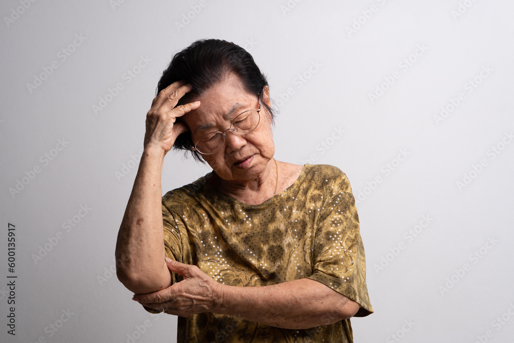 A senior woman who has a severe headache suffers from a stroke ,brain disease,patient holding head with her hand,suffering from senile dementia,memory disorders, confused old elderly with Alzheimer - obrazy, fototapety, plakaty 