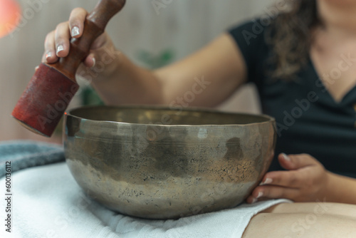 Sound massage, treatment with Tibetan bowls in the spa salon. Female meditation during traditional Nepalese practices using the vibration of bronze bowls for energy recovery