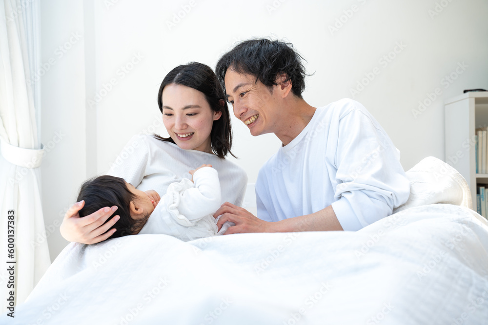 ベッドで子供の面倒を見る日本人の親子 ベッドで子供の面倒を見る日本人の親子