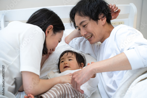 ベッドで子供の面倒を見る日本人の親子