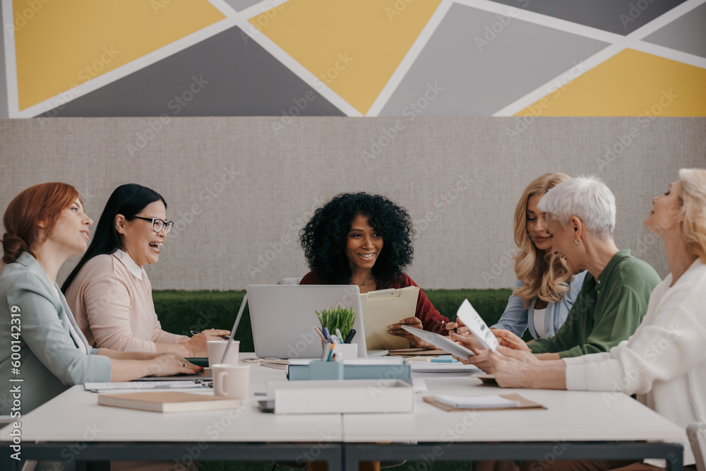 Fototapeta premium Group of mature women discussing business while having meeting in the office