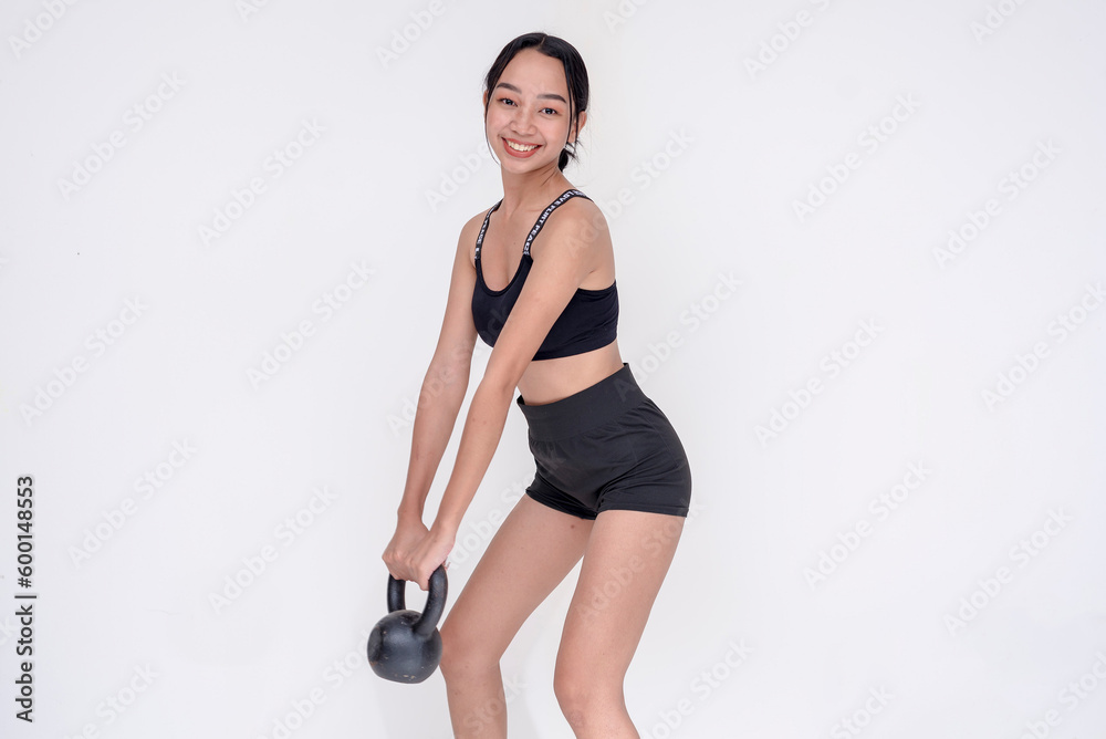A happy and fit young woman weightlifting by holding a kettle bell, side view. Isolated on a white background. A happy and fit young woman weightlifting by holding a kettle bell, side view. Isolated on a white background.