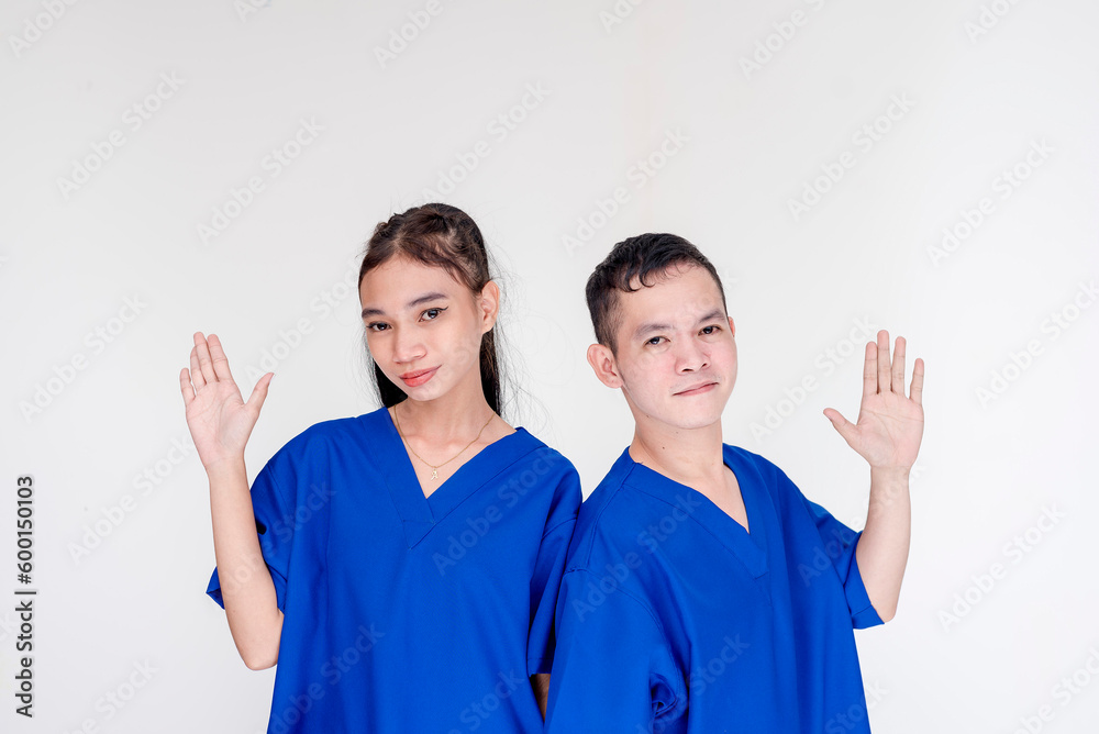 Two young and dedicated caregivers posing with their hands up and palm facing the camera. Nurses saying hello. Isolated on a white background. Two young and dedicated caregivers posing with their hands up and palm facing the camera. Nurses saying hello. Isolated on a white background.