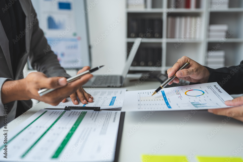 A group of business analysts discuss the summary graph report on business expenses and work information about the company's financial statements. A group of business analysts discuss the summary graph report on business expenses and work information about the company's financial statements.