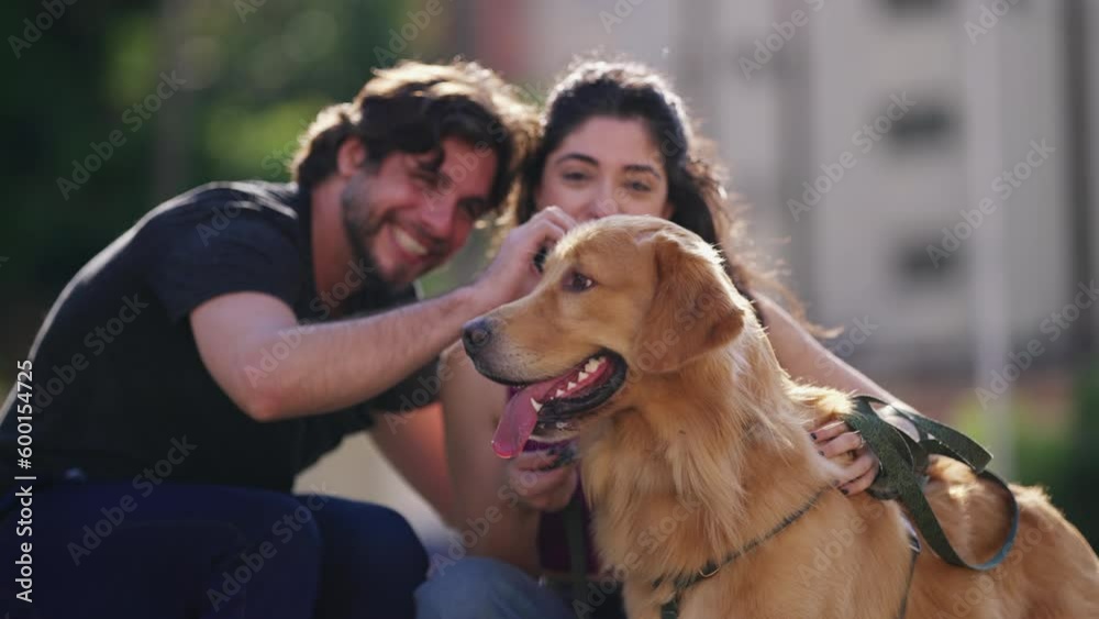 Couple posing for a photo with their beloved Golden Retriever Pet in outdoor setting. Candid moment of man and woman affectionately caressing their canine companion Couple posing for a photo with their beloved Golden Retriever Pet in outdoor setting. Candid moment of man and woman affectionately caressing their canine companion