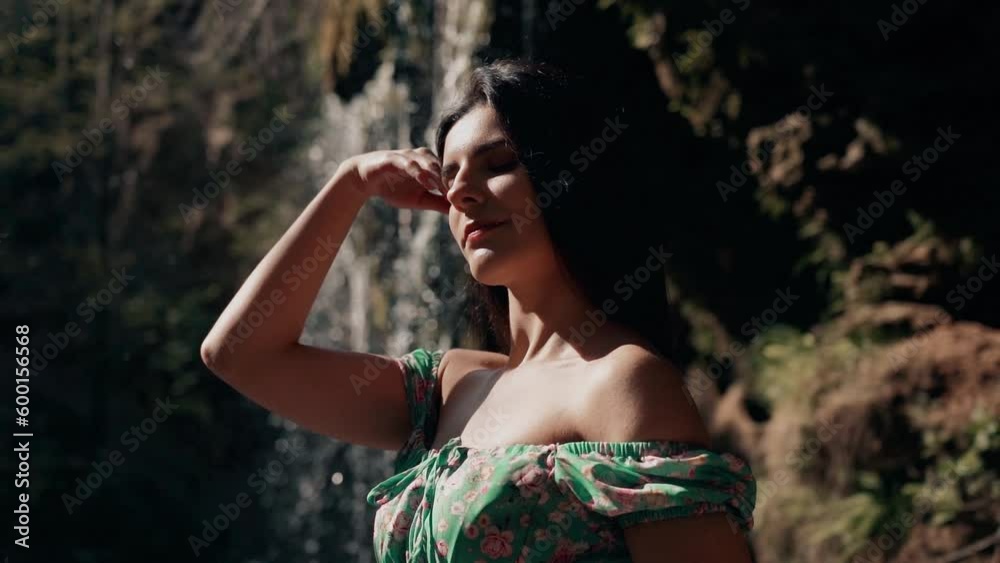 Beautiful model in a turquoise dress posing near a mountain waterfall.Wildlife concept