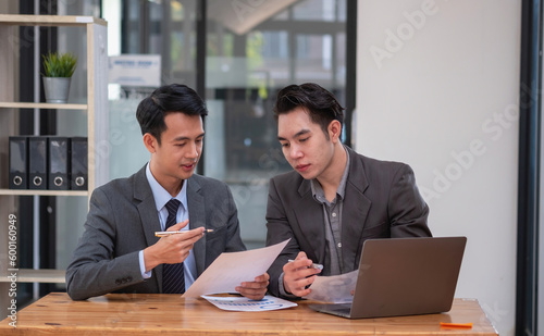 Asian business team consists of marketing staff. accountant and financial officer Help each other analyze company profits using tablets. calculator Laptop computers, graph paper, and corporate pens.