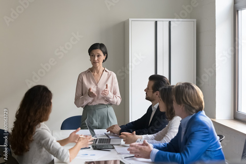 Executive team listen to mature female CEO presenting project plans for coming year, explain corporate strategy. Business trainer lead seminar for diverse staff members in company board room. Training