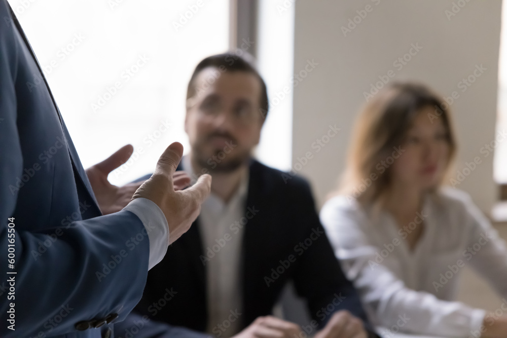 Unknown businessman, project leader in formal suit gesticulates while makes speech or presentation, talk at group meeting, close up cropped view. Communication, negotiations, mentoring, seminar event - obrazy, fototapety, plakaty 