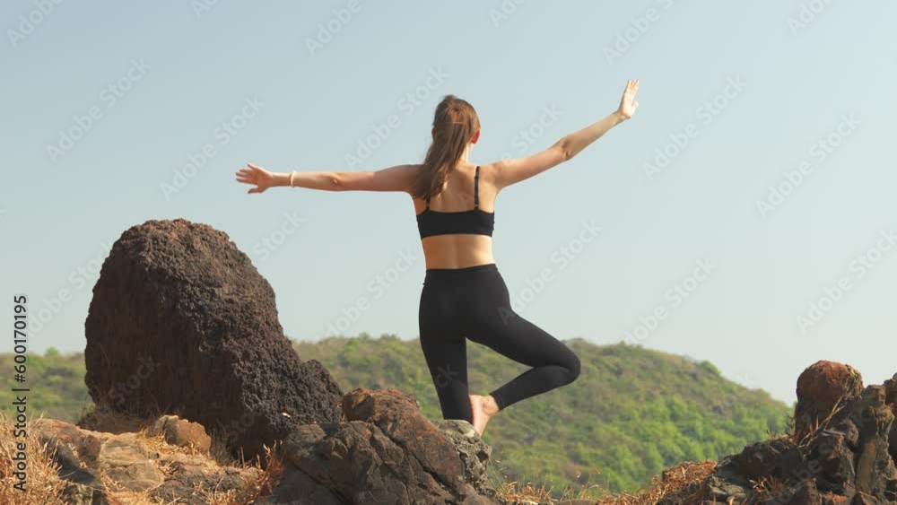 Back view young woman is standing in Vrikshasana Pose Back view young woman is standing in Vrikshasana Pose