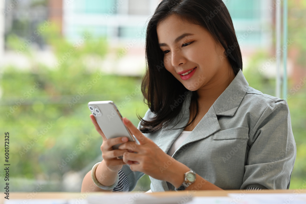 Cropped image with Pleasant asian businesswoman checking social media on mobile phone. Cropped image with Pleasant asian businesswoman checking social media on mobile phone.