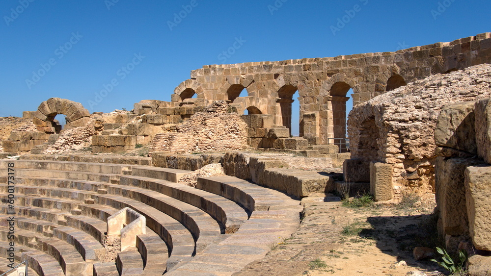 Wall with stone arched windows above the stadium seating in the amphitheater in the Roman ruins at Uthina, outside of Tunis, Tunisia