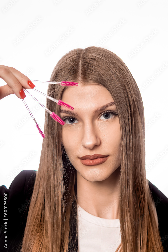 A young girl holds brushes for eyebrows and eyelashes in her hand A young girl holds brushes for eyebrows and eyelashes in her hand