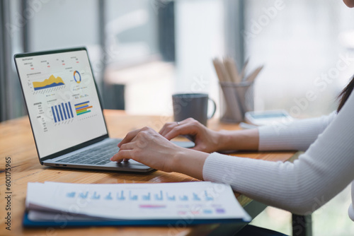 Foto Businesswoman accountant using a graphs and charts to analyze market data, balance sheets,accounts,and net profits in order to plan new sales strategies and increase production capacity