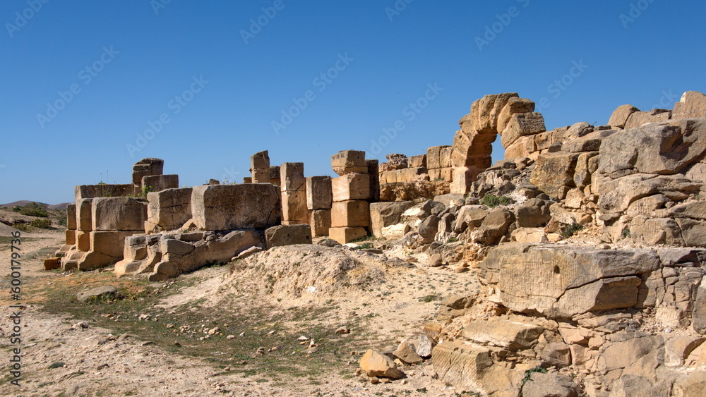 Stone arch among the rubble of an old wall in the amphitheater in the Roman ruins at Uthina, outside of Tunis, Tunisia