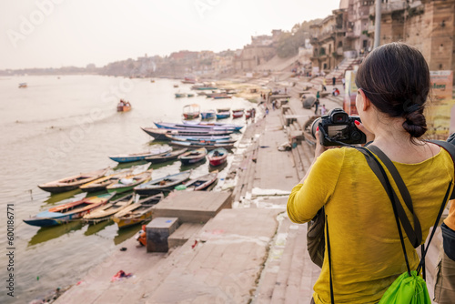 A tourist woman takes pictures of boats on the Ganges River in Varanasi.