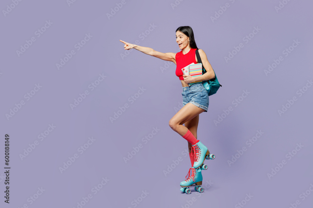 Full body young latin woman wear red casual clothes rollers backpack rollerblading point index finger aside on area hold books isolated on plain pastel purple background. Summer sport leisure concept.