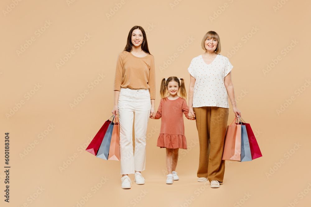 Full body women wear casual clothes with child kid girl 6-7 years old. Granny mother daughter hold shopping package bags isolated on plain beige background Family parent day Black Friday sale concept Full body women wear casual clothes with child kid girl 6-7 years old. Granny mother daughter hold shopping package bags isolated on plain beige background Family parent day Black Friday sale concept
