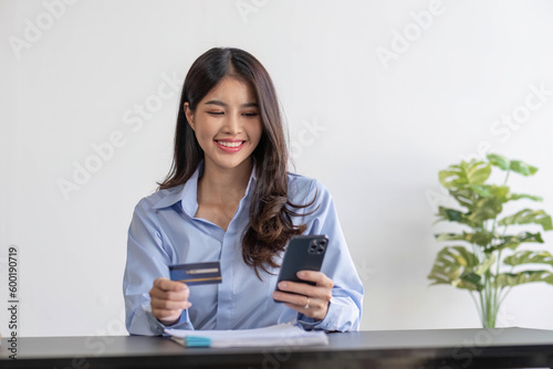 A beautiful asian woman using credit card for purchasing and shopping online on mobile phone