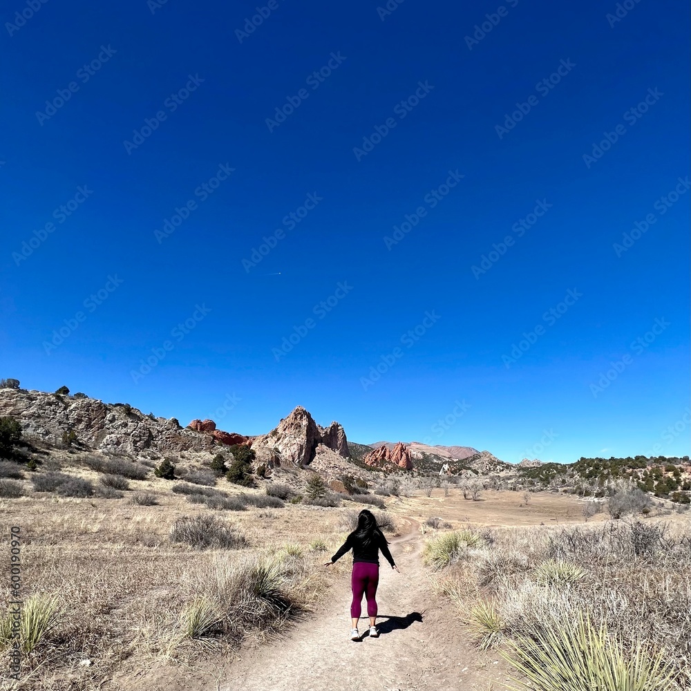 woman on a hiking trail with the garden of the gods park as the landscape background