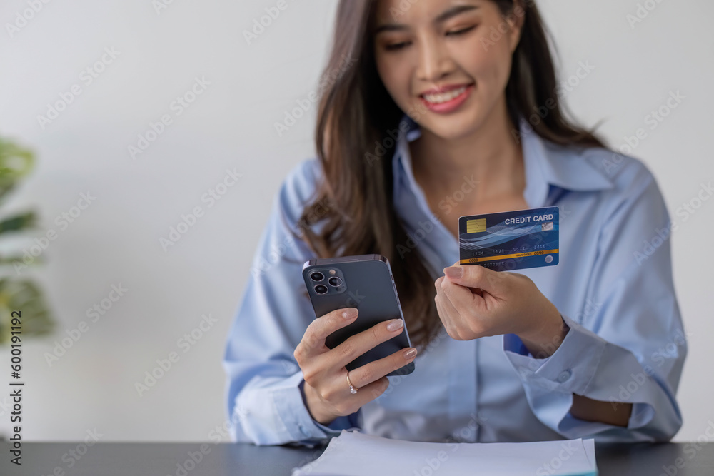A beautiful asian woman using credit card for purchasing and shopping online on mobile phone A beautiful asian woman using credit card for purchasing and shopping online on mobile phone