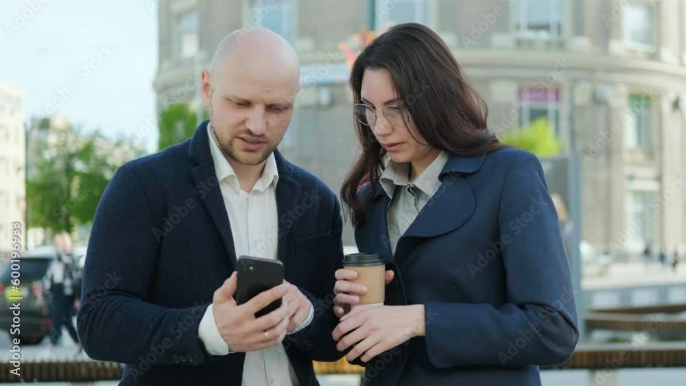 A man in a blue suit explains something to a woman, pointing to a smartphone. Business concept A man in a blue suit explains something to a woman, pointing to a smartphone. Business concept