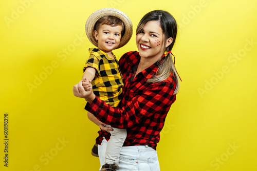 Mother and her baby son celebrating the Brazilian Festa Junina. Portrait of a woman and her son wearing typical clothes and a straw for the traditional June festival in Brazil.