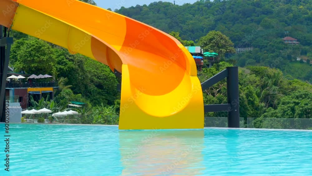 Woman in swimwear slides down a water slide in a swimming pool. Girl having fun, going down a water slide. Sliding at a water amusement park on summer vacation.