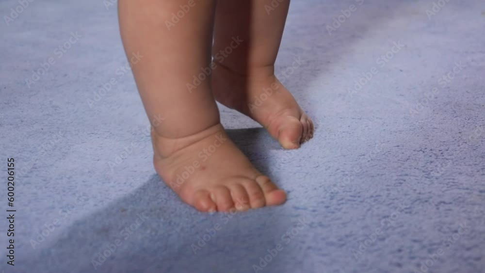 Chubby baby feet take first steps on a blue blanket in the playpen Chubby baby feet take first steps on a blue blanket in the playpen