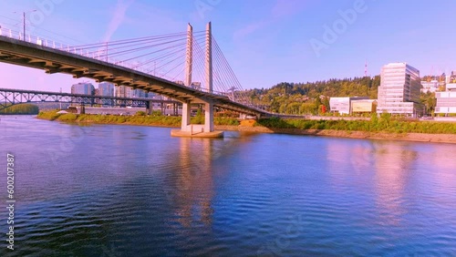 A beautiful aerial flying backwards of Tilikum Crossing Bridge's twin towers, cables, and stunning architecture with fishing boats in Portland, just above the water.