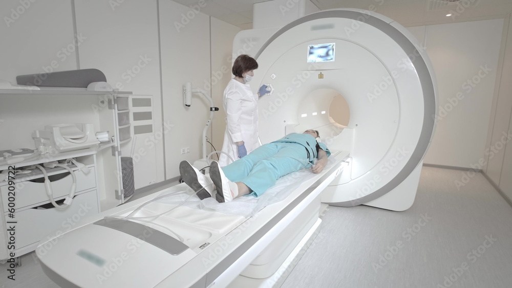 The doctor performs an MRI scan for a patient at the clinic. The girl lies in the MRI device. Magnetic resonance imaging in the study of the human body. Modern technologies in medicine The doctor performs an MRI scan for a patient at the clinic. The girl lies in the MRI device. Magnetic resonance imaging in the study of the human body. Modern technologies in medicine
