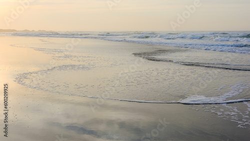 Sunrise over waves flowing up beach sand