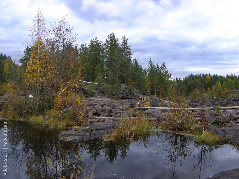 A rocky landscape with trees and rocks in the foreground. Suna River, Poor Porog Waterfall, Girvas, Republic of Karelia, Russia