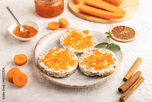 Carrot jam with puffed rice cakes on gray concrete. Side view.