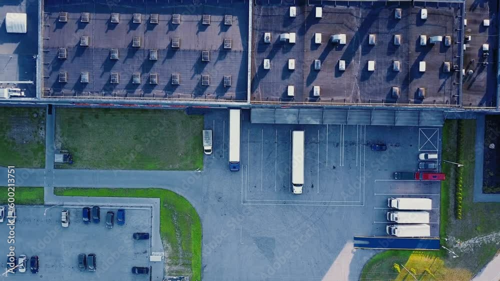Aerial view of goods warehouse. Logistics center in industrial city zone from above. Aerial view of trucks loading at logistic center. View from drone.