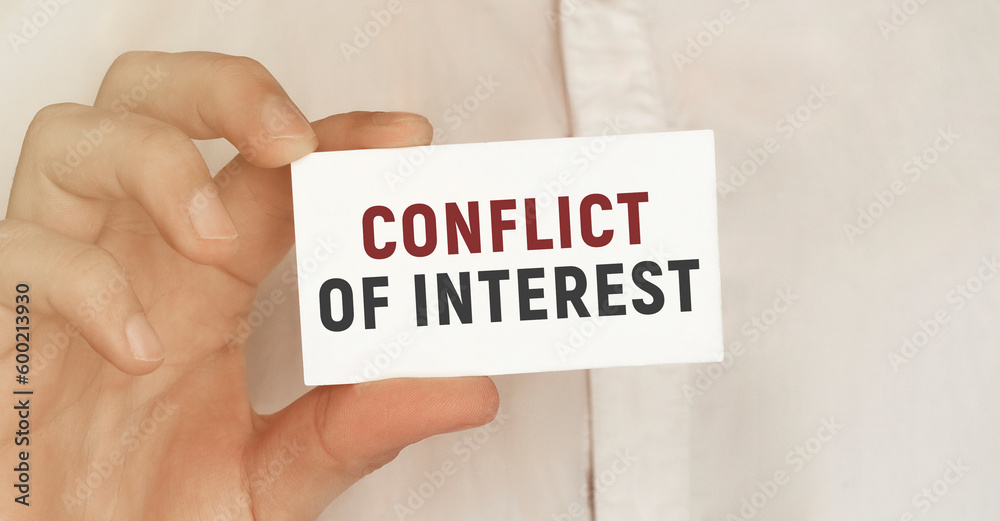 Card with text Conflict of interest in a man's hand Card with text Conflict of interest in a man's hand